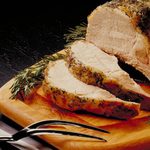 mcc-baked-meat-with-apples-500×500 Sliced pork served on a chopping board with rosemary sprigs
